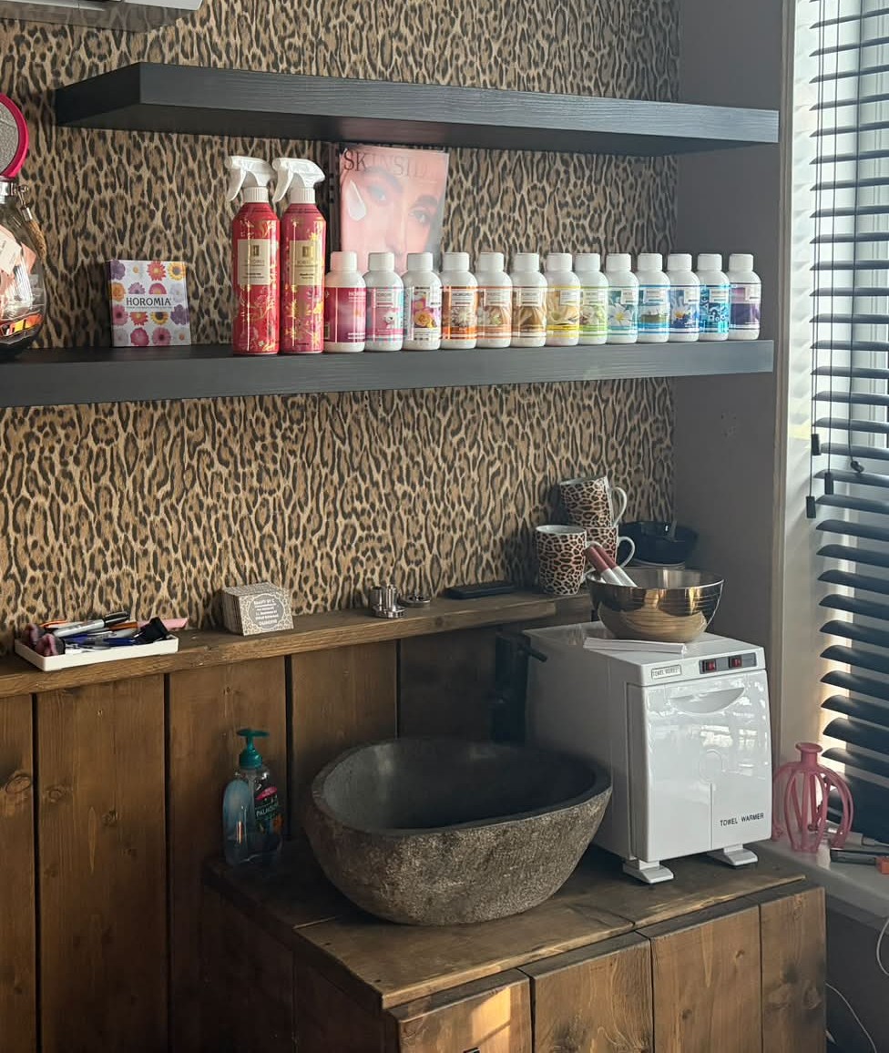 De salon van Beauty by C met luipaardbehang, planken met producten en een stenen waskom